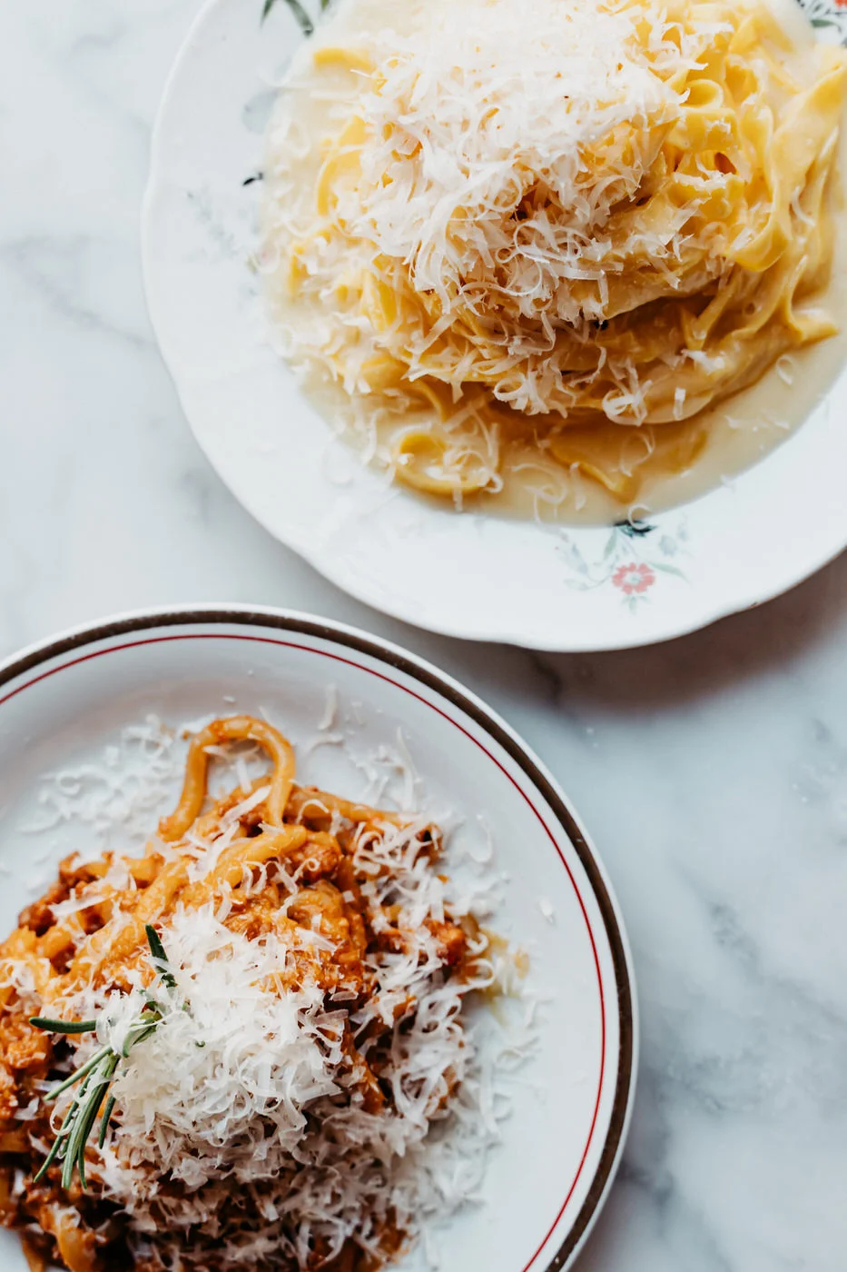 Tagliatelle with parmesan and spaghetti in tomato-meat sauce on marble