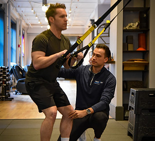 Therapist coaching an athlete with a TRX trainer