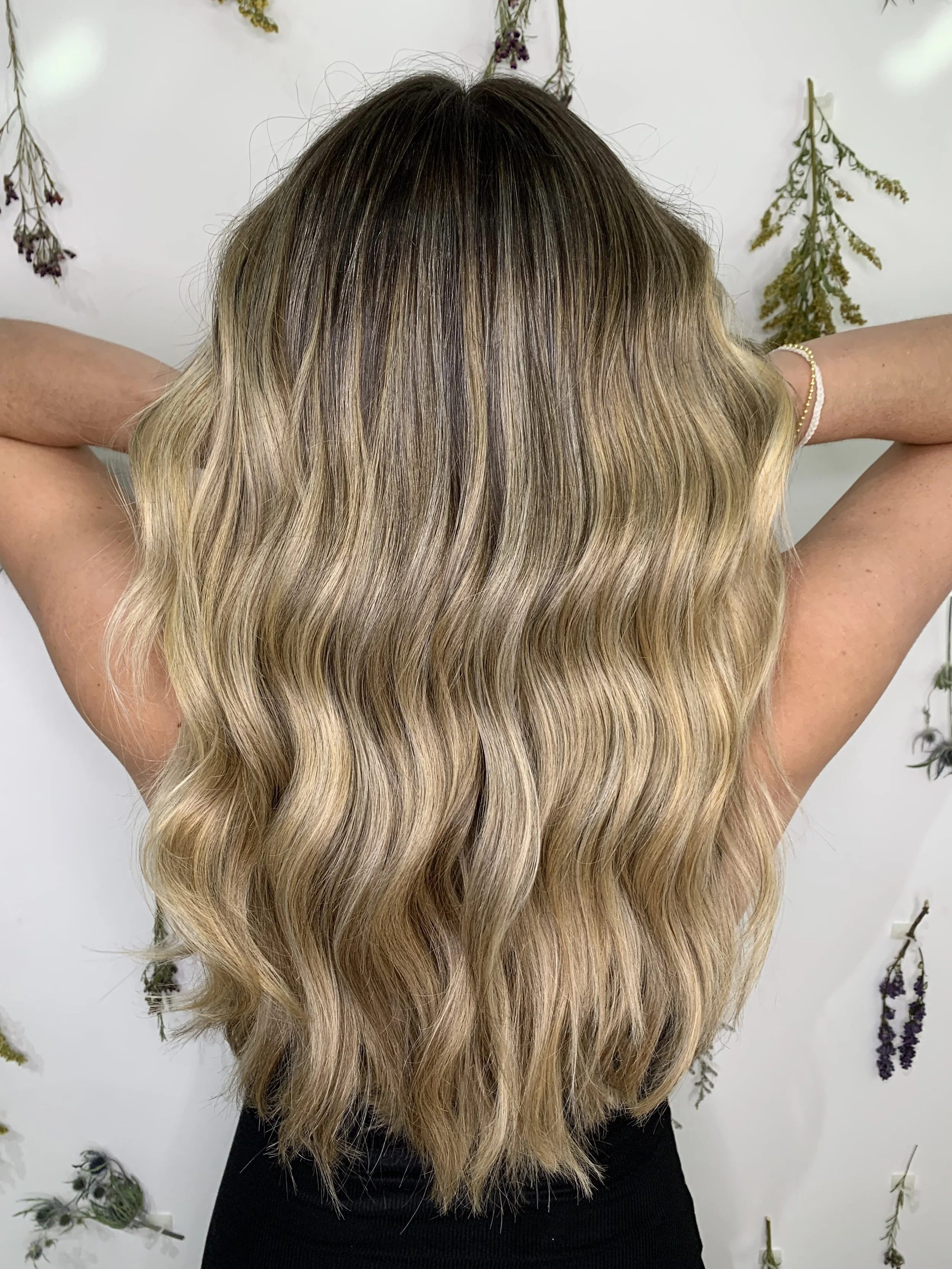 Long blonde balayage against the dried flower wall