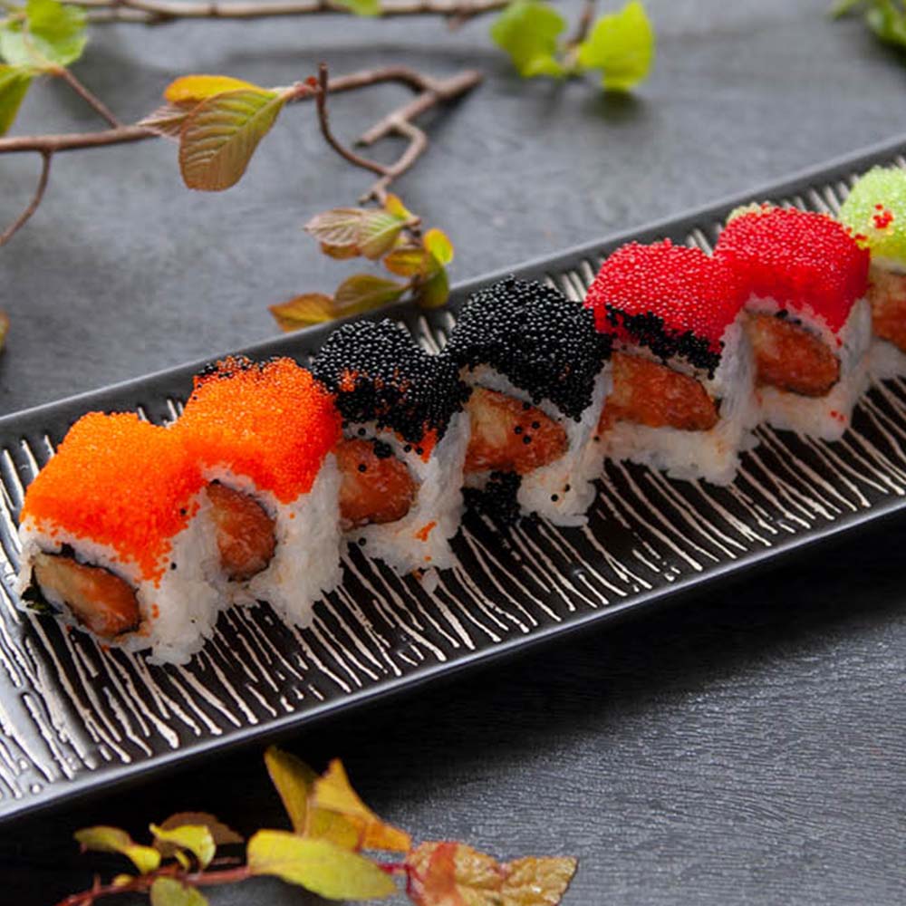 Sushi rolls topped with orange, black and red roe on a dark plate