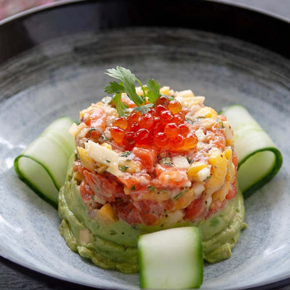 Salmon tartare tower with ikura on avocado purée and cucumber ribbons