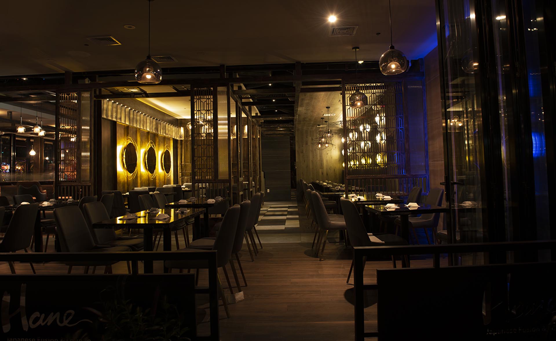 Hane dining room at night with gold wall discs and dark wood lattice screens