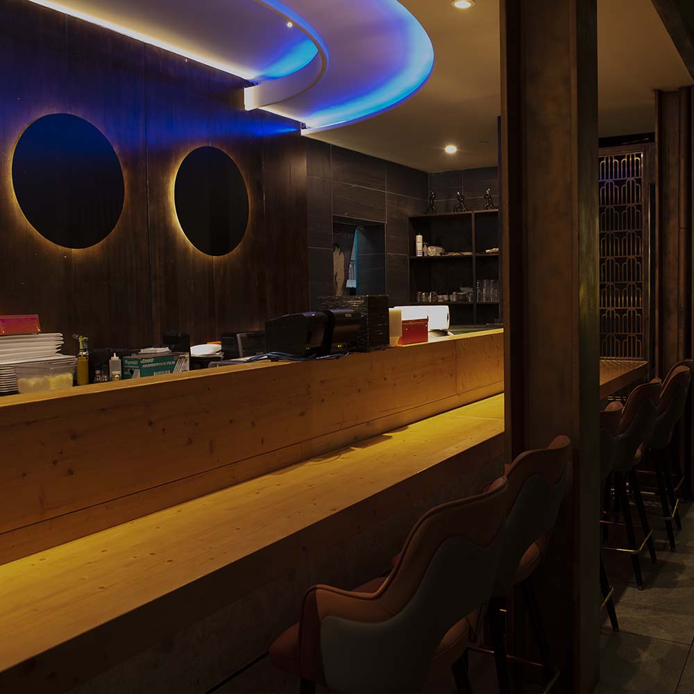 Hane sushi counter with wooden bar top and circular wall mirrors