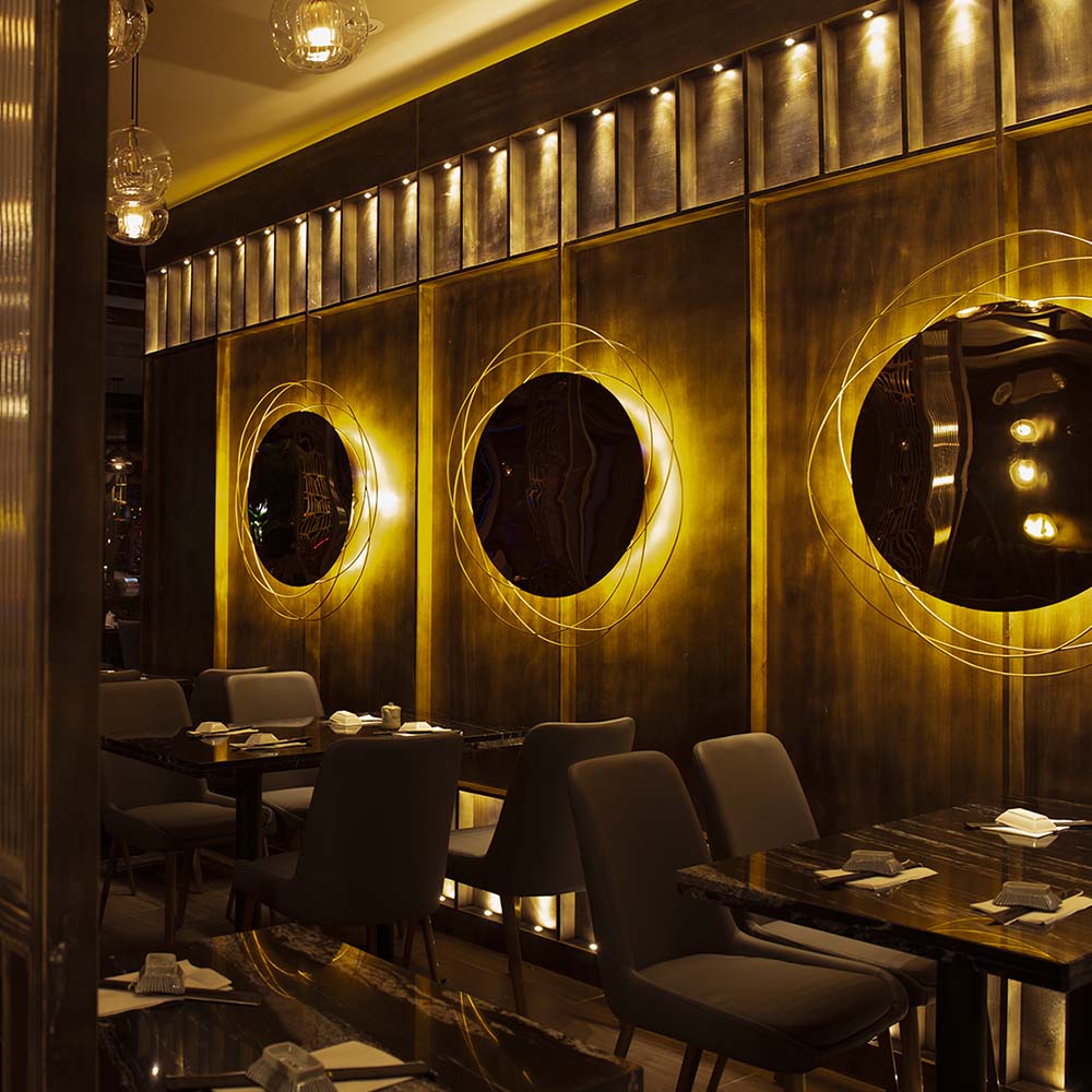 Signature gold circular backlit wall art with set tables at Hane