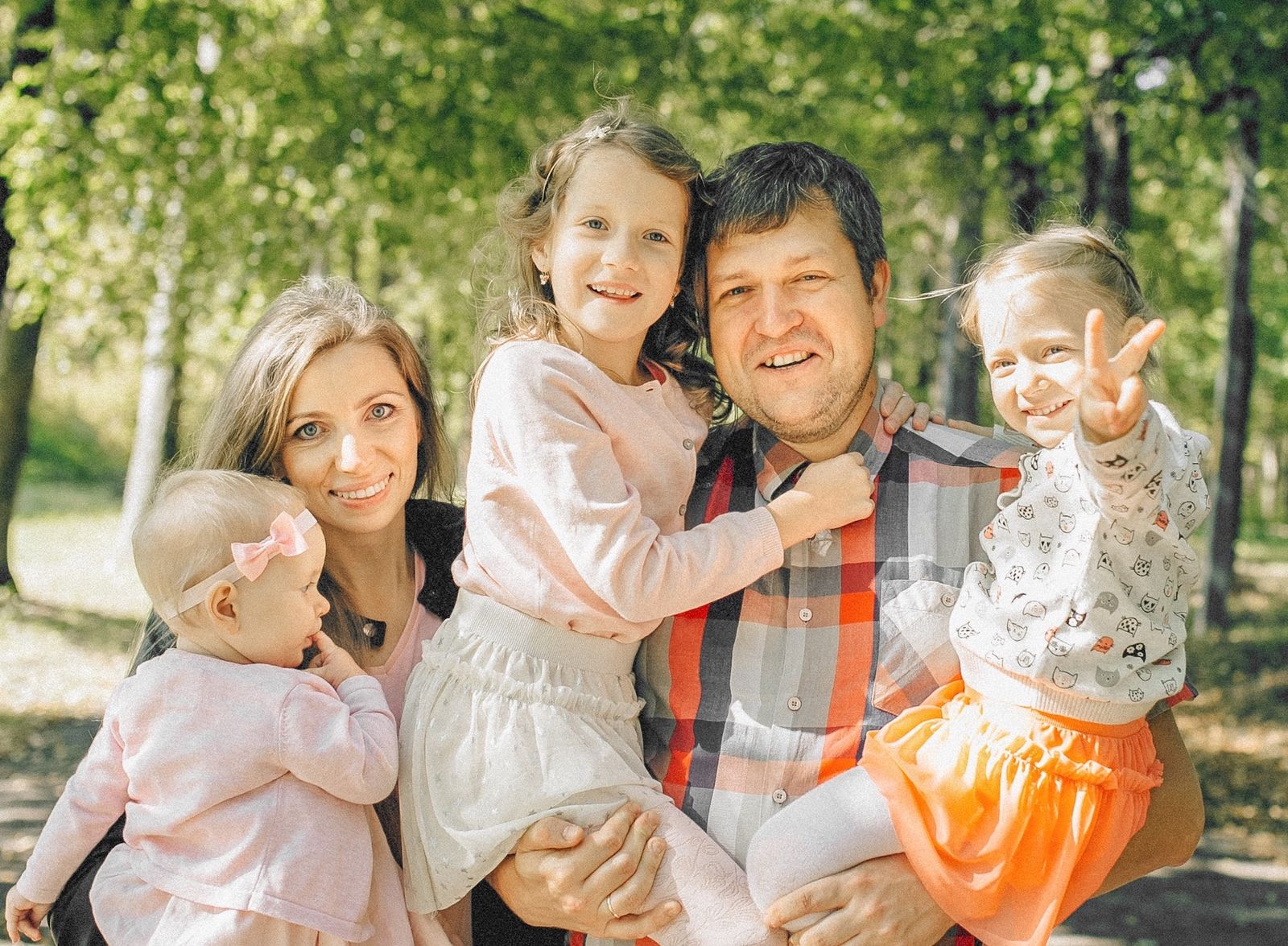 A smiling family of five outdoors in a sunlit park