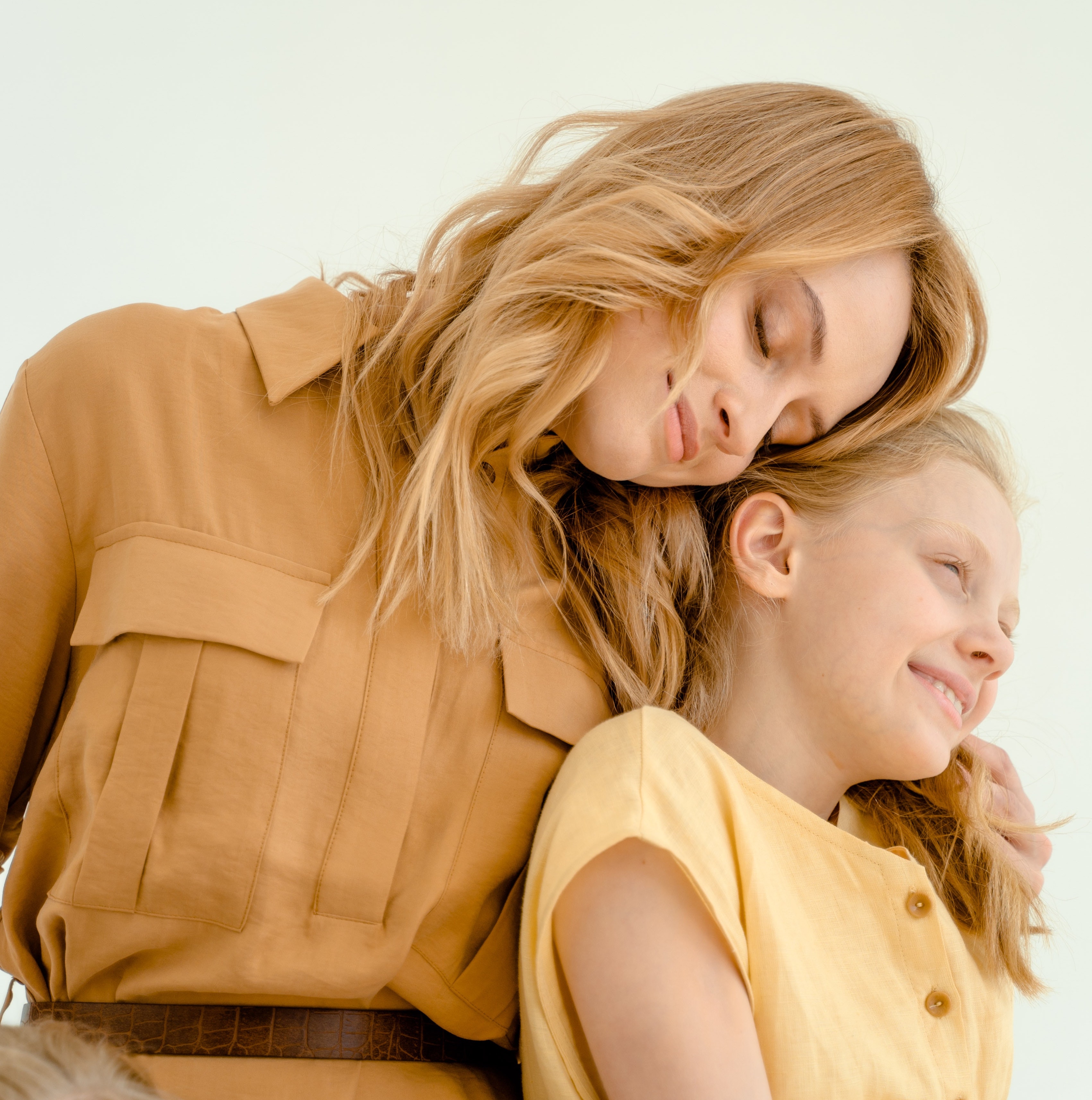 A mother leaning over a smiling young girl