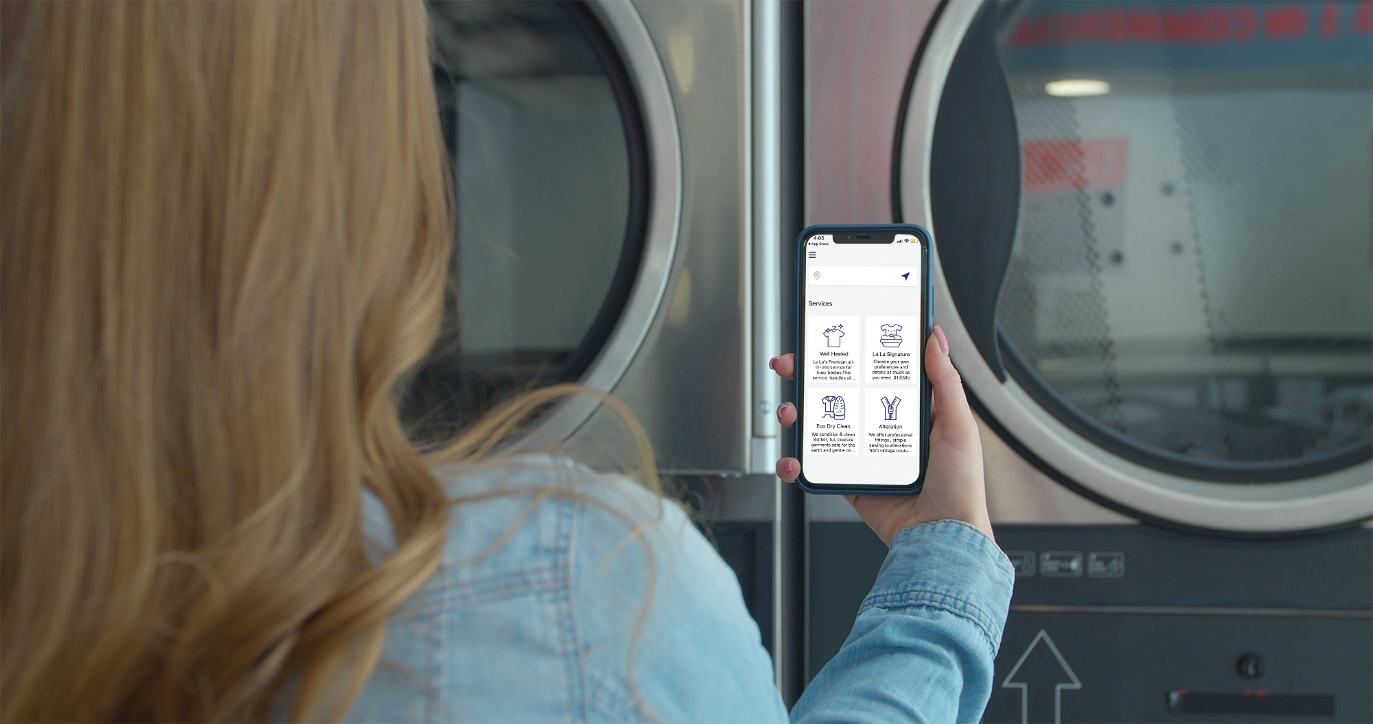Customer at the La La Laundry laundromat holding a phone with the La La Laundry app open