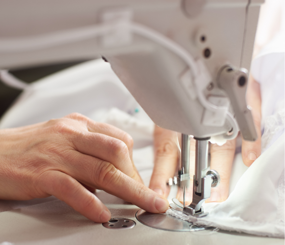 Hands guiding fabric under a sewing machine needle