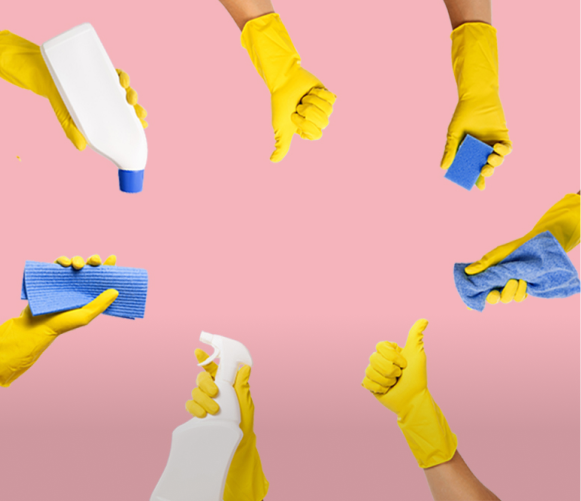 Yellow-gloved hands holding cleaning supplies on a pink background