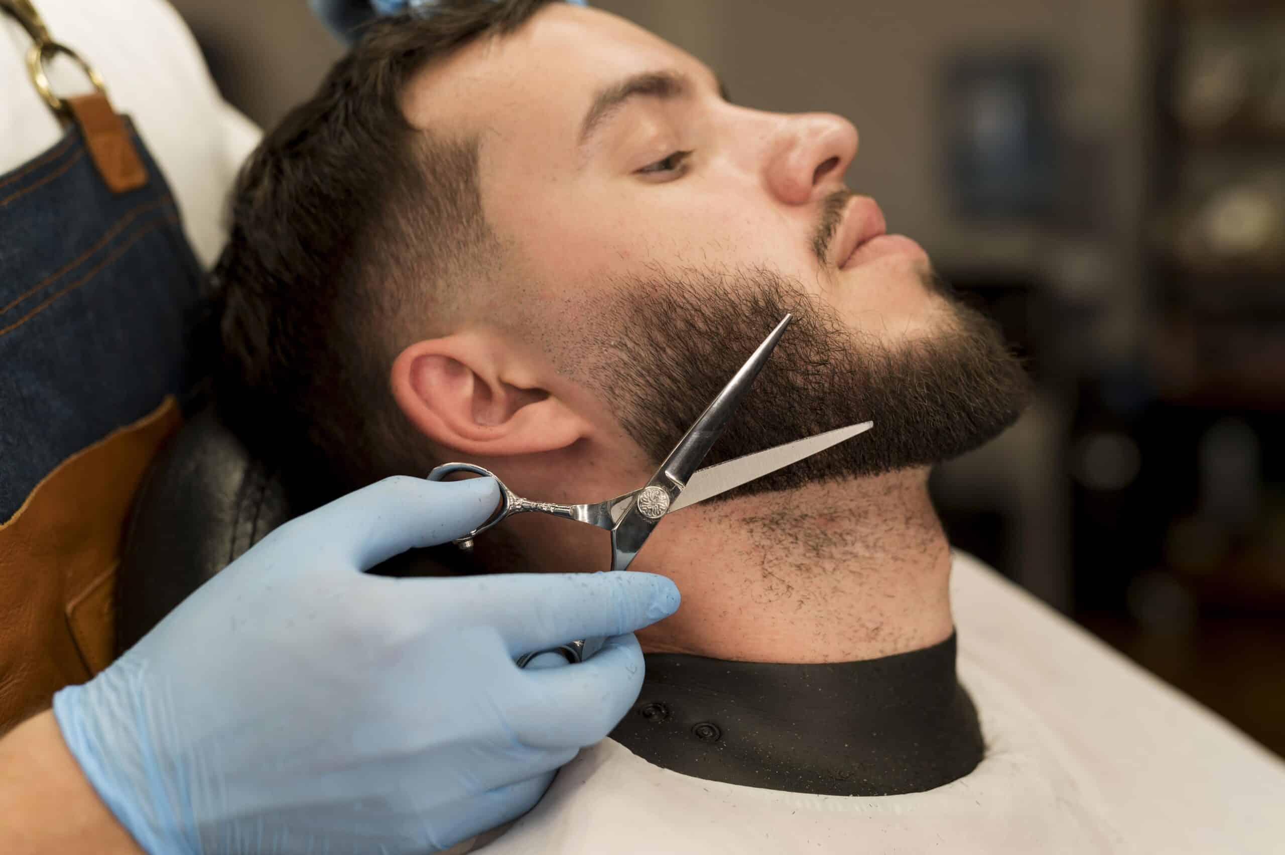 Barber trimming a client's beard with scissors