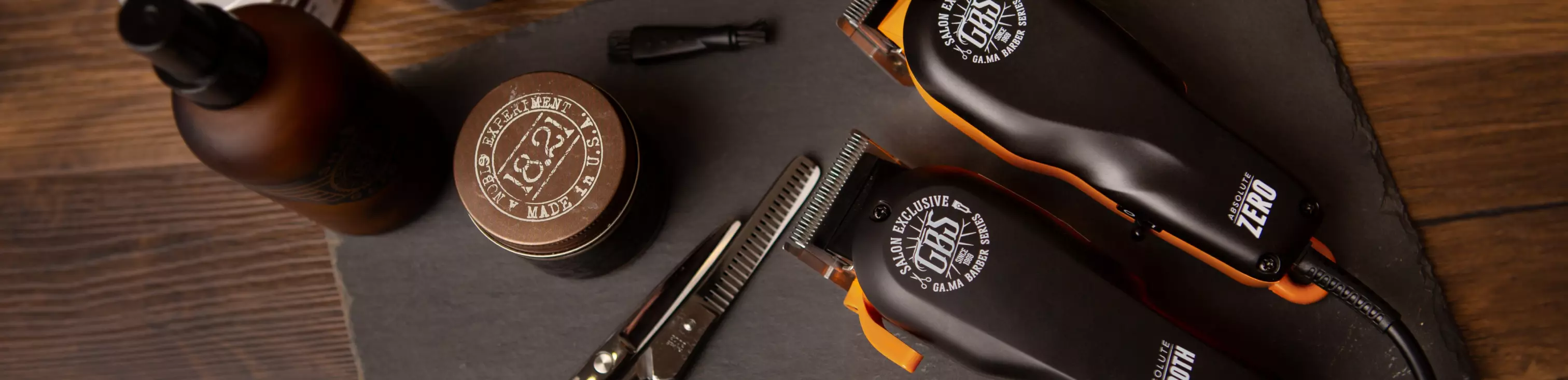 Barbershop tools laid out: clippers, straight razor, pomade tin and spray bottle