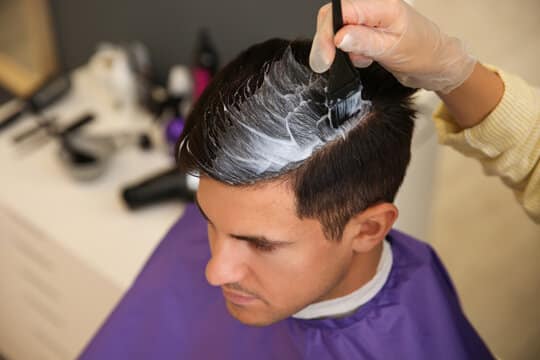 Barber applying hair color to a client's scalp