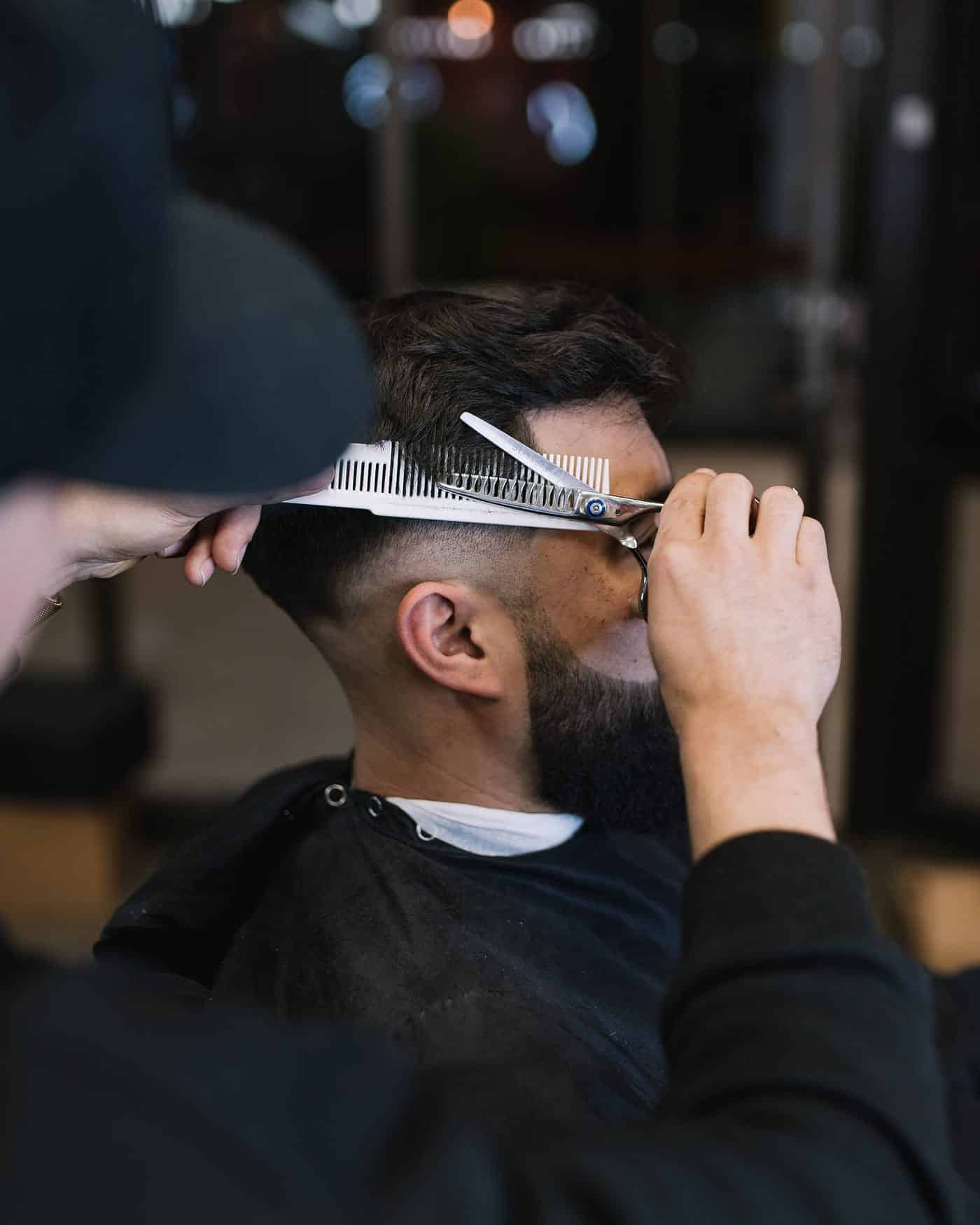 Barber cutting hair with comb and scissors