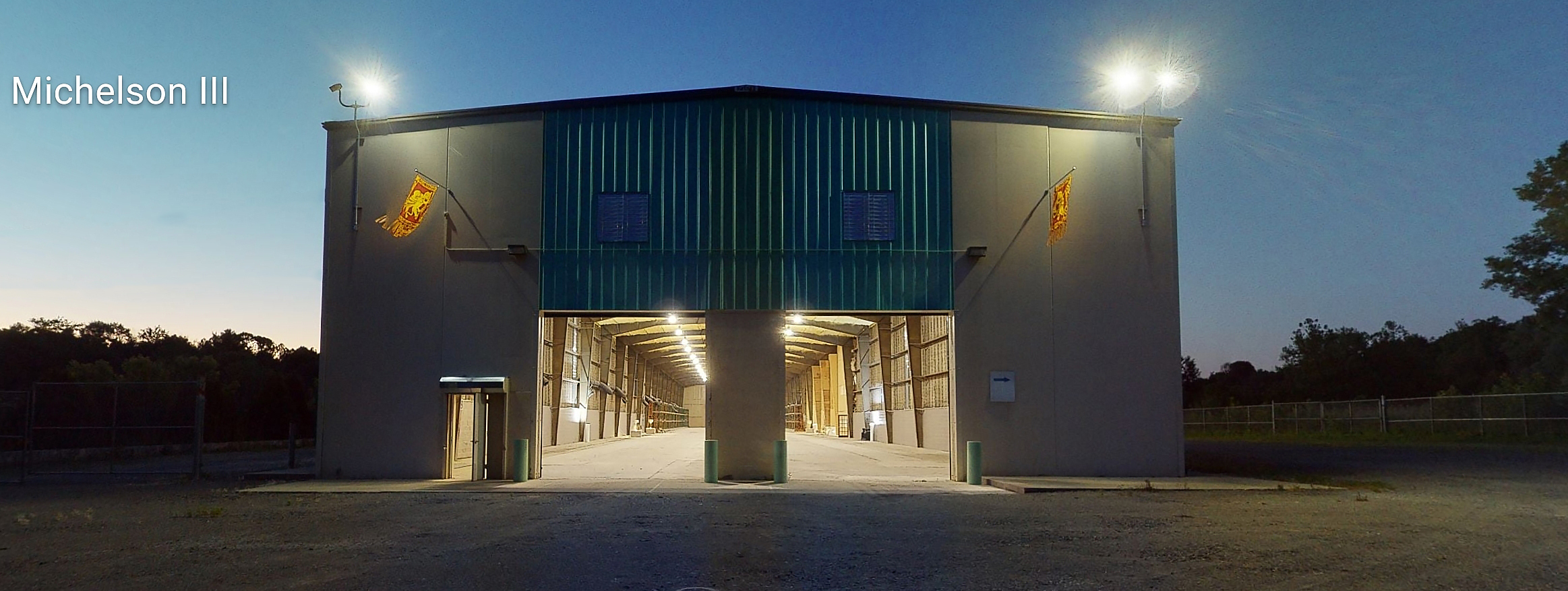 Exterior night shot of a large industrial warehouse labeled Michelson III with illuminated open bay doors