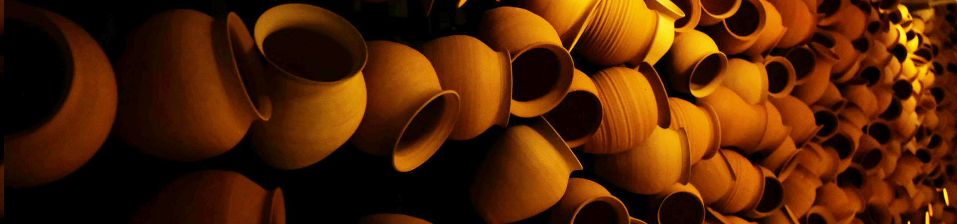 Close-up of stacked terracotta clay pots lit with warm amber light at Pylos