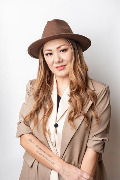Mariko, Redge Salons stylist, long wavy hair with a brown fedora and tan blazer