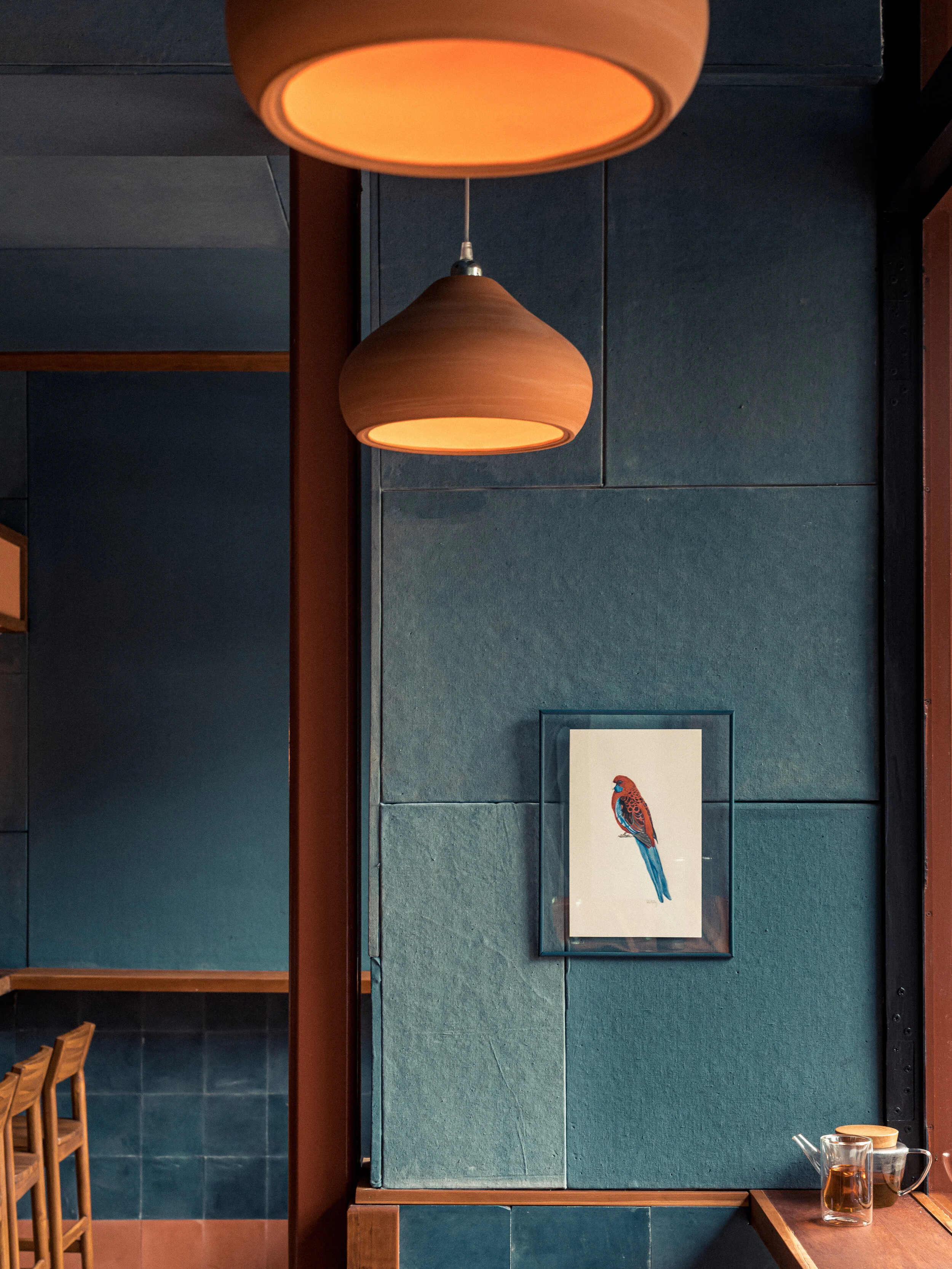Rosella's dining room — glazed teal tile walls, warm pendant lighting and a framed rosella print