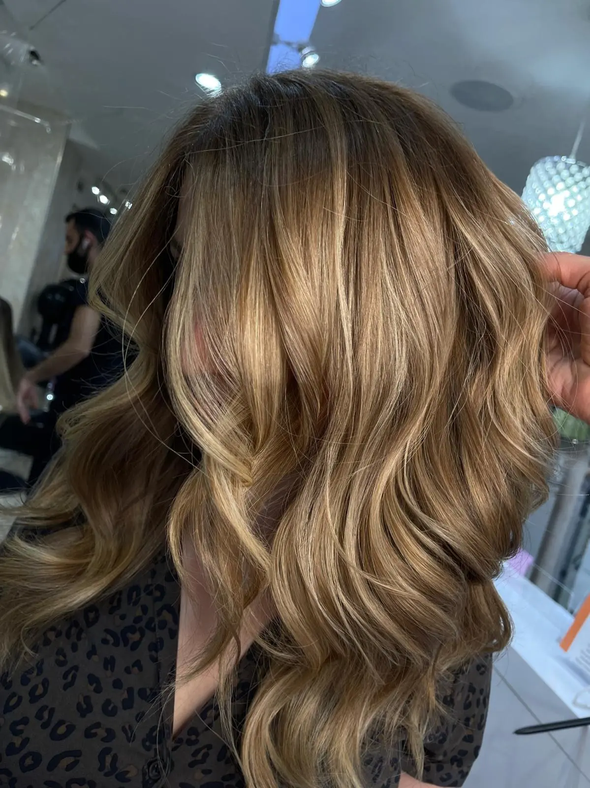 Honey golden balayage waves in front of the salon mirror
