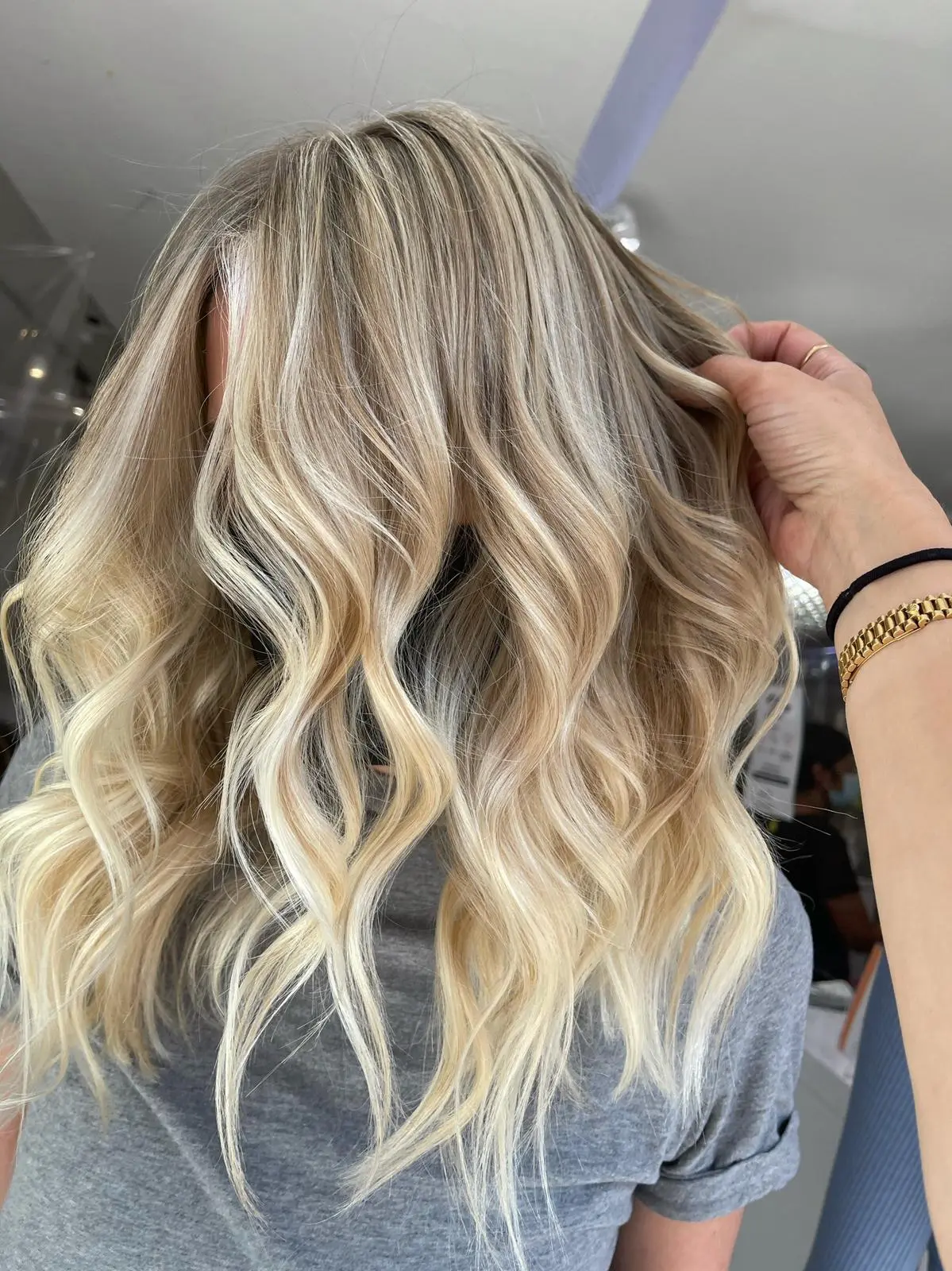 Long ash blonde balayage waves with hand running through