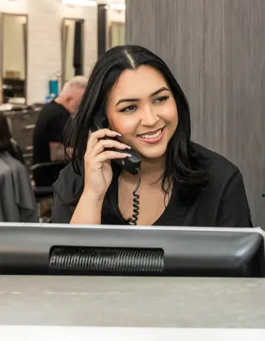 Receptionist smiling on the phone at the Shear Bliss NYC front desk
