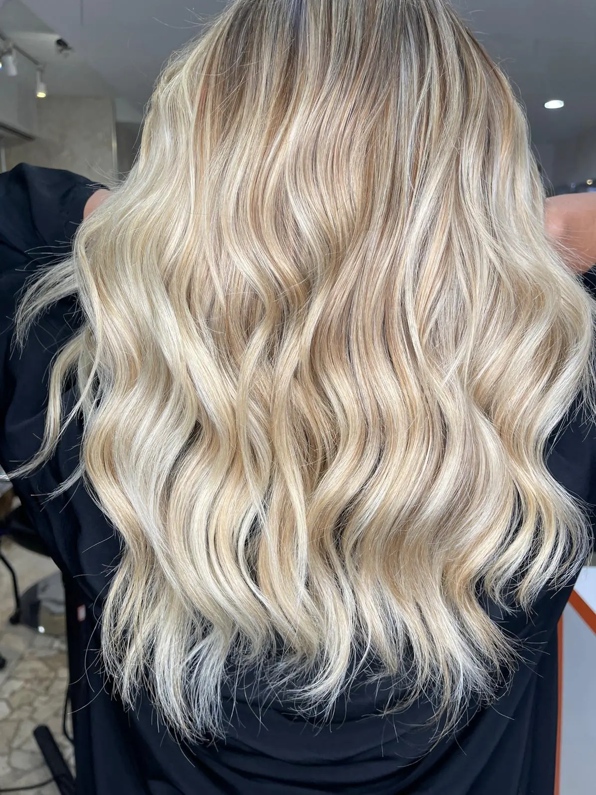 Long platinum blonde waves with dark salon cape