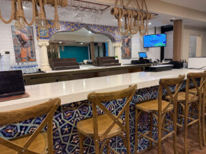 Taftoon's bar with a white marble counter, wooden barstools and colorful mosaic tile floor