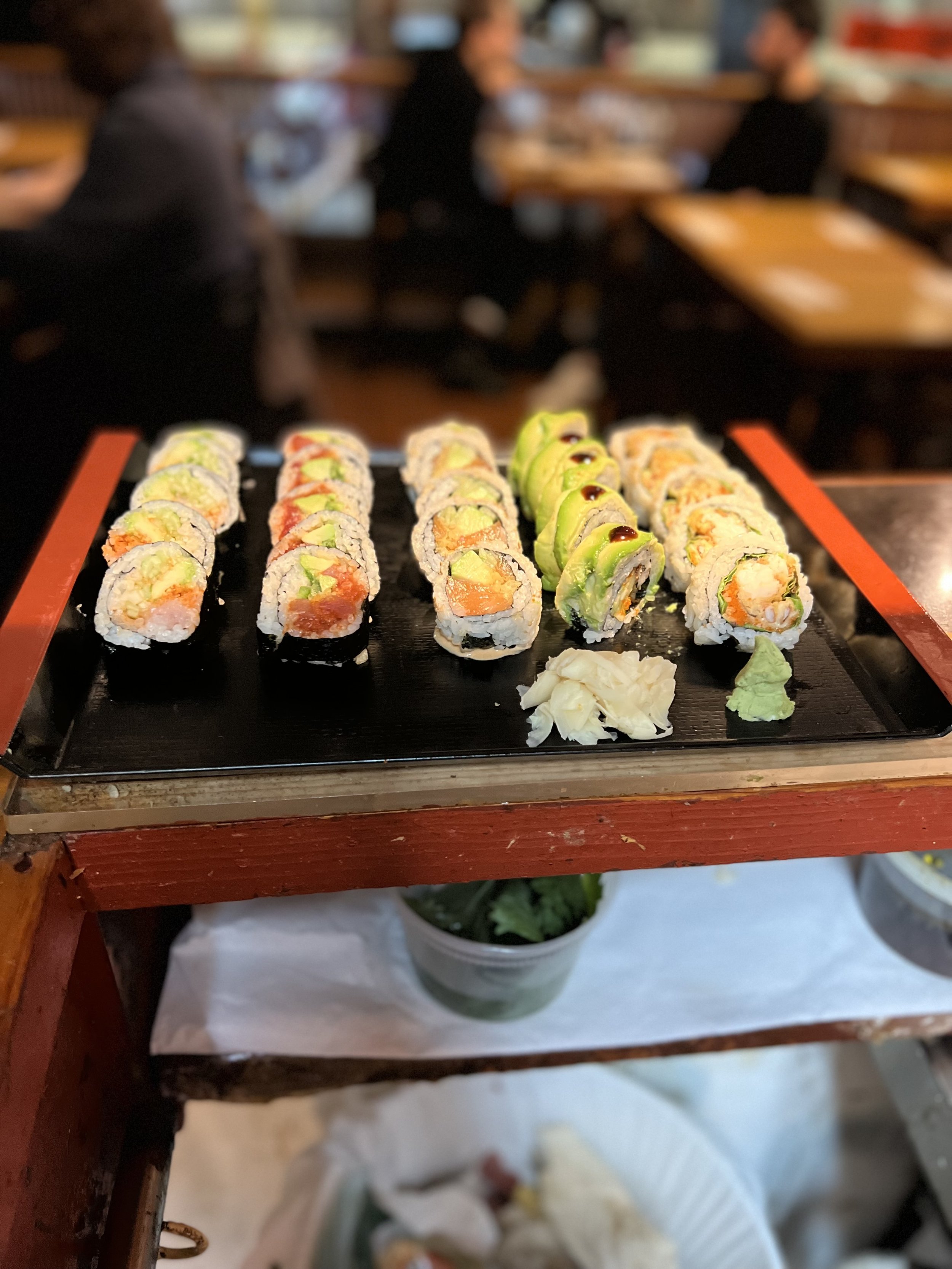 Sushi rolls on a black tray atop the red service cart
