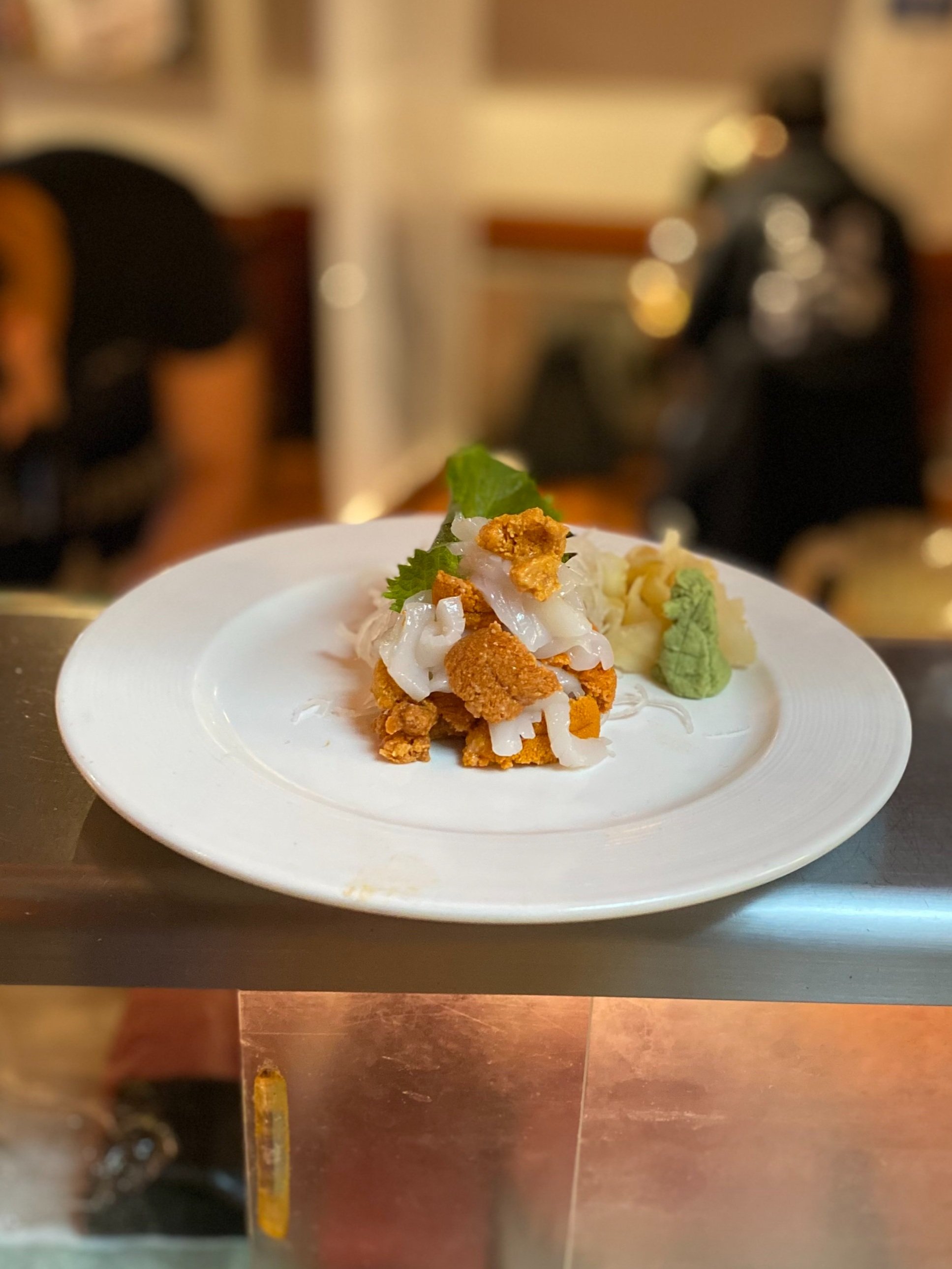 Sea urchin (uni) with squid and ikura on a white plate at the sushi bar