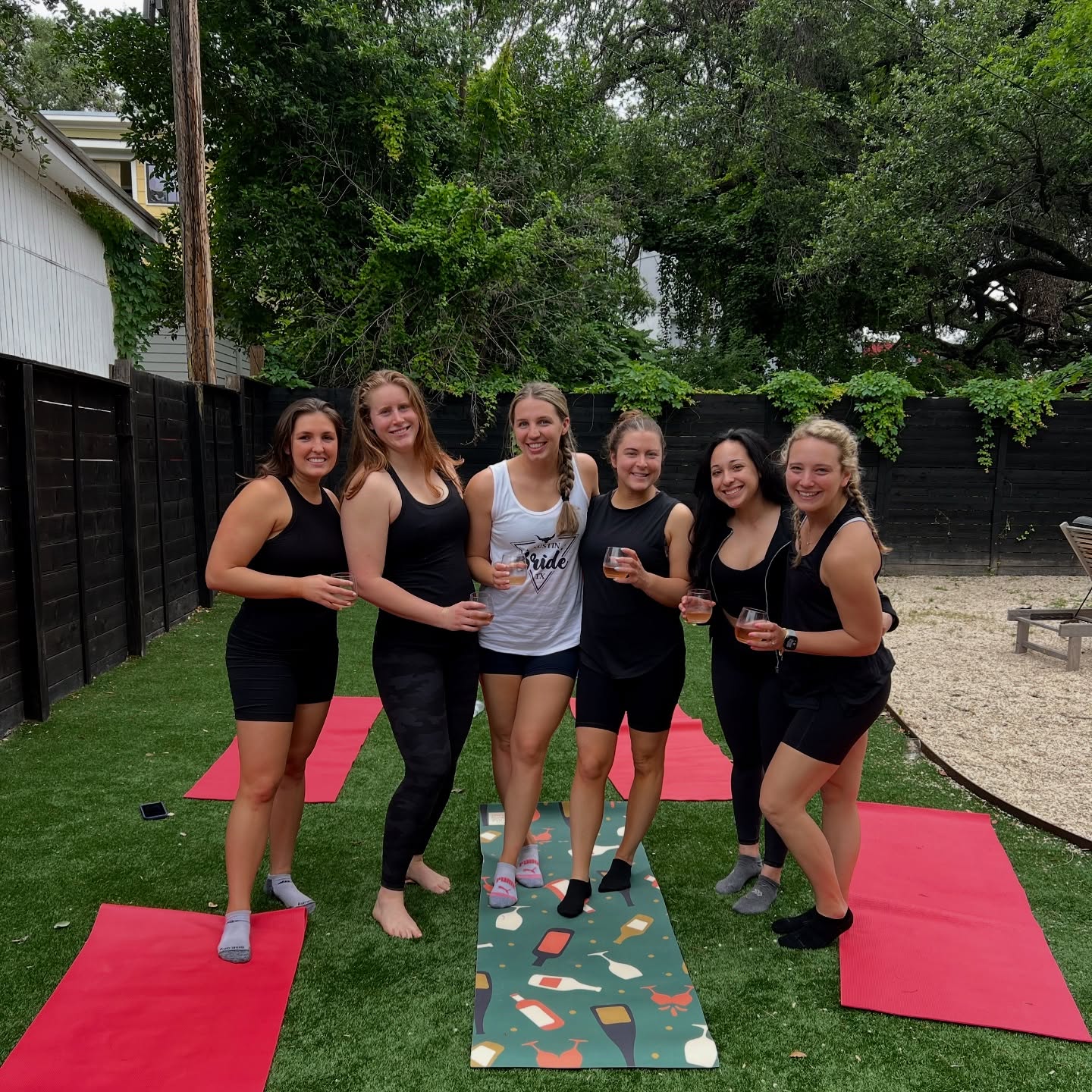 Group including a bride on colorful mats holding wine glasses