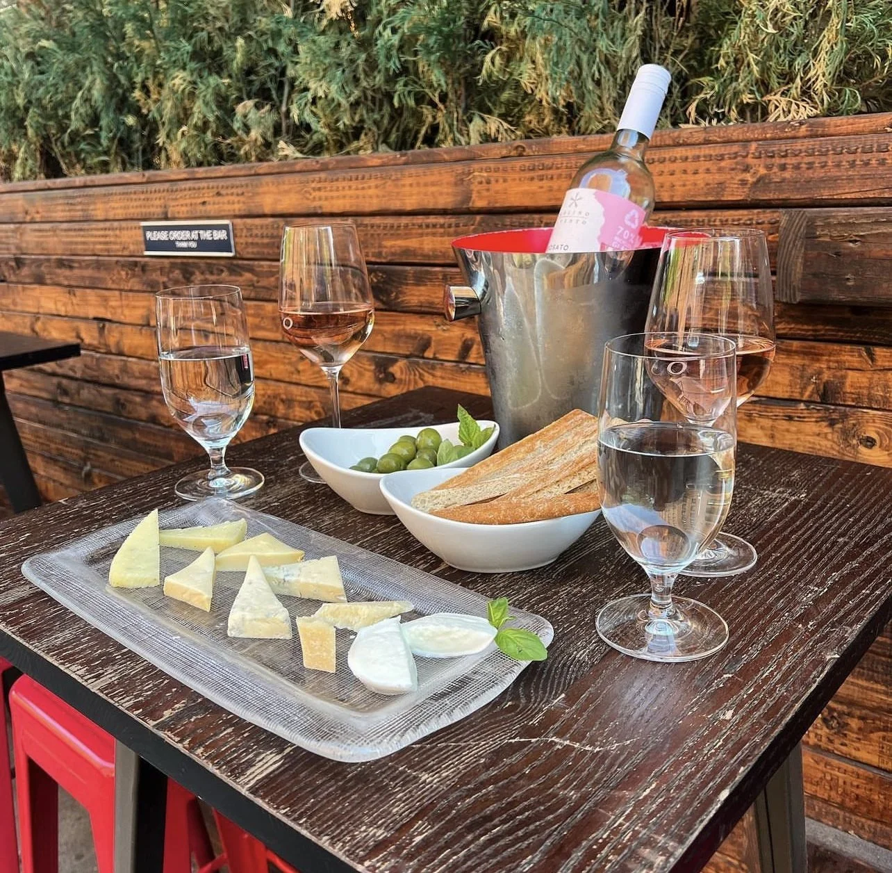Outdoor table with rosé in an ice bucket, cheese plate, olives and bread