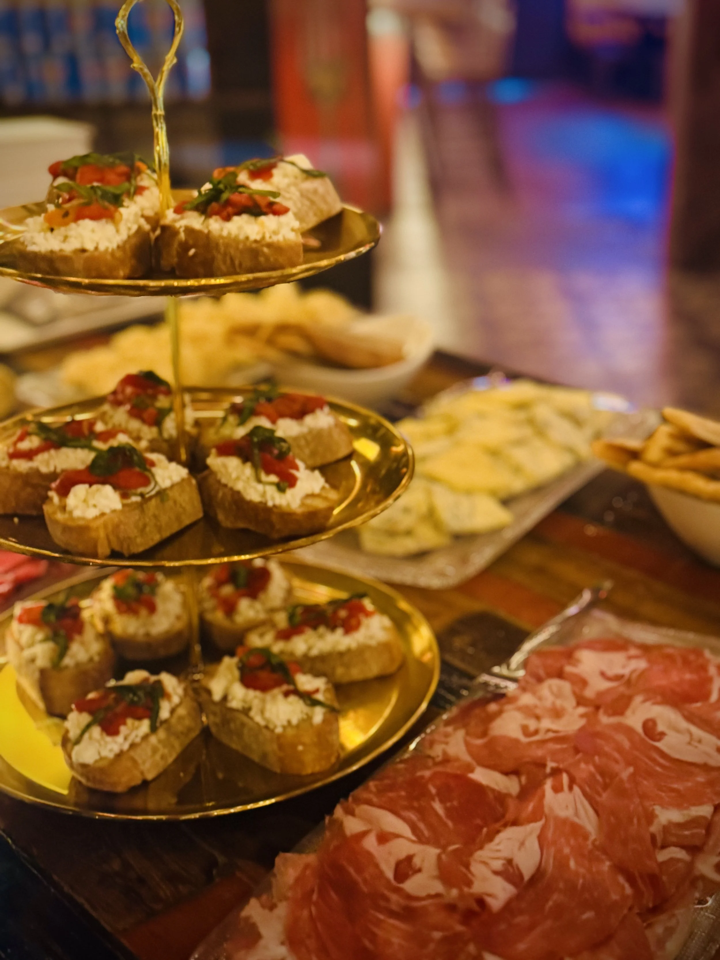 Three-tier gold stand of bruschette with ricotta and roasted red peppers