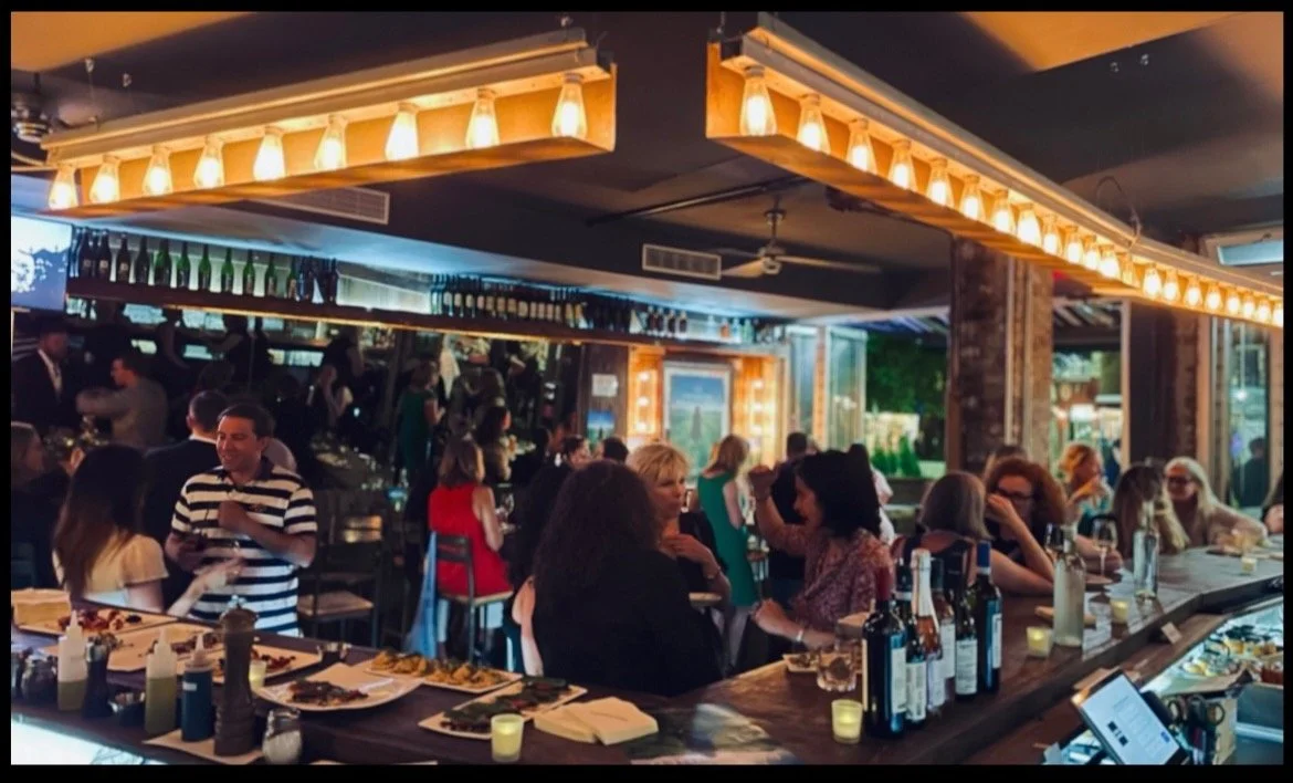 Bar Veloce East Village — a busy semi-outdoor bar packed with guests under Edison pendant lights