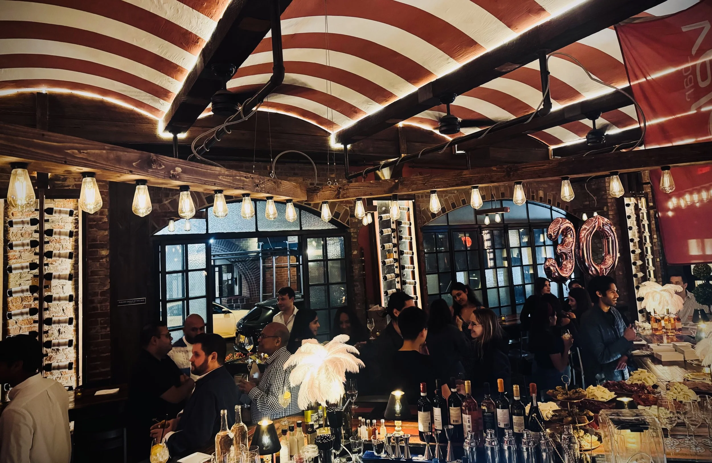 Party at Bar Veloce Bacaro under the red and white striped arched ceiling with a crowd of guests