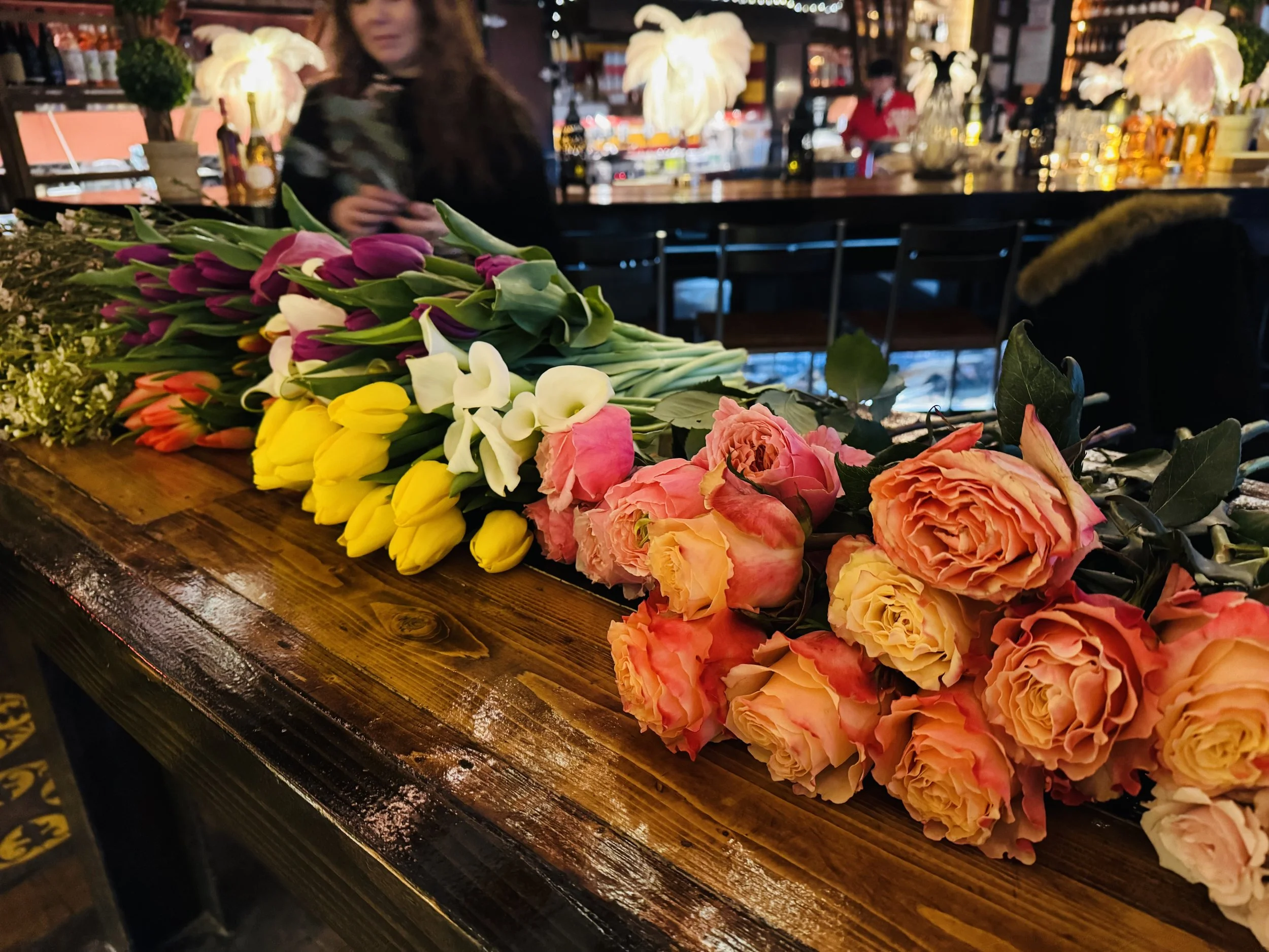 Fresh flower bouquets laid across the wooden bar counter