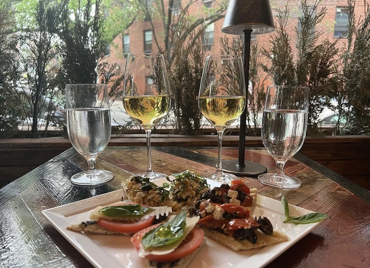Window table with a plate of bruschette and two glasses of white wine