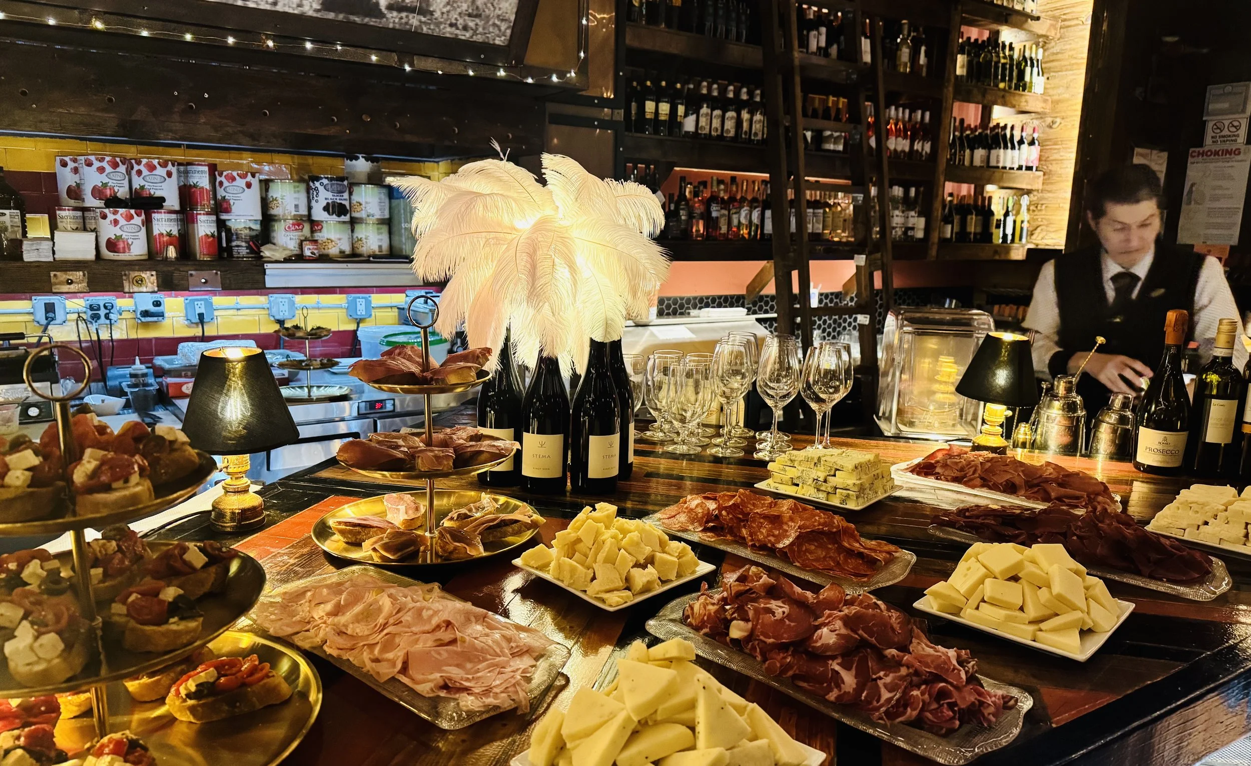 Aperitivo spread of charcuterie, cheese and bruschette laid along the bar