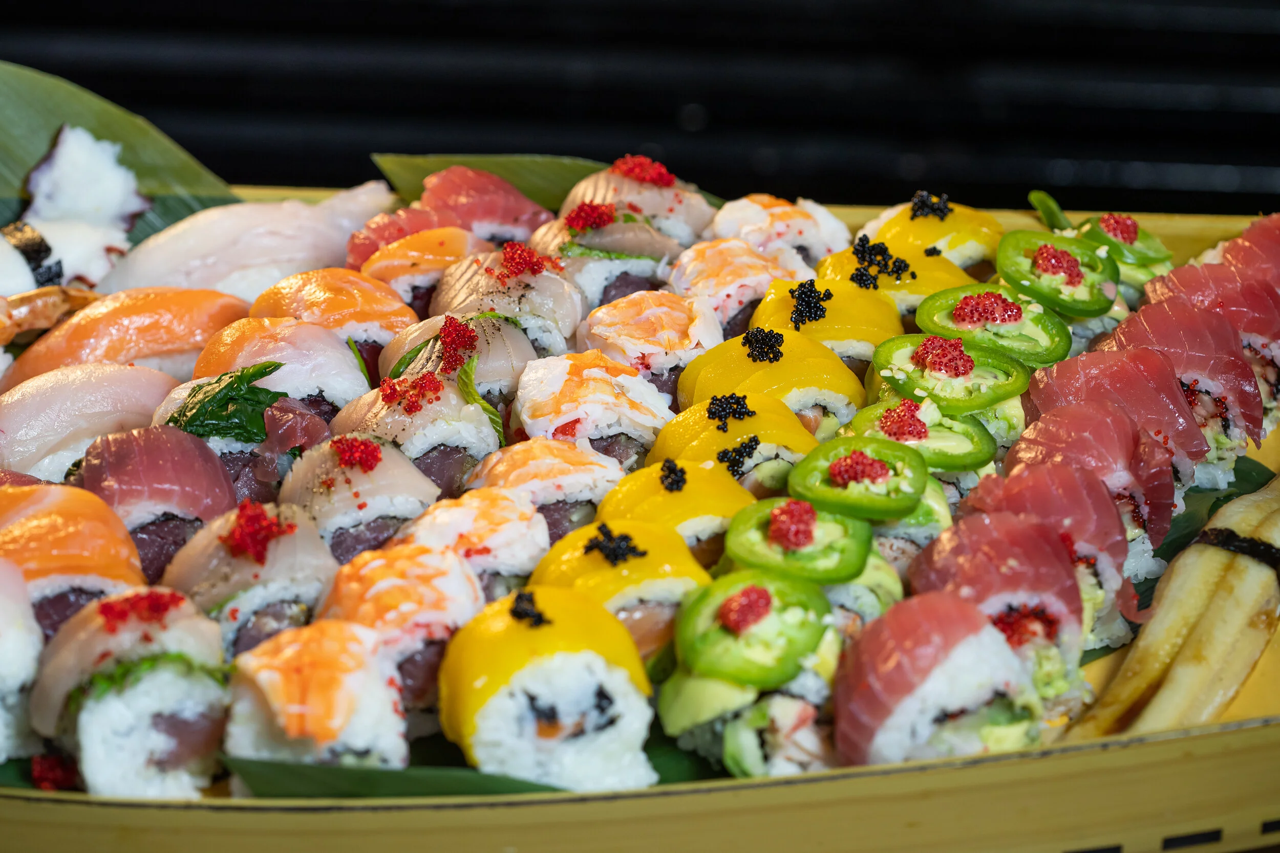 Large sushi and maki platter arranged in a yellow bamboo boat