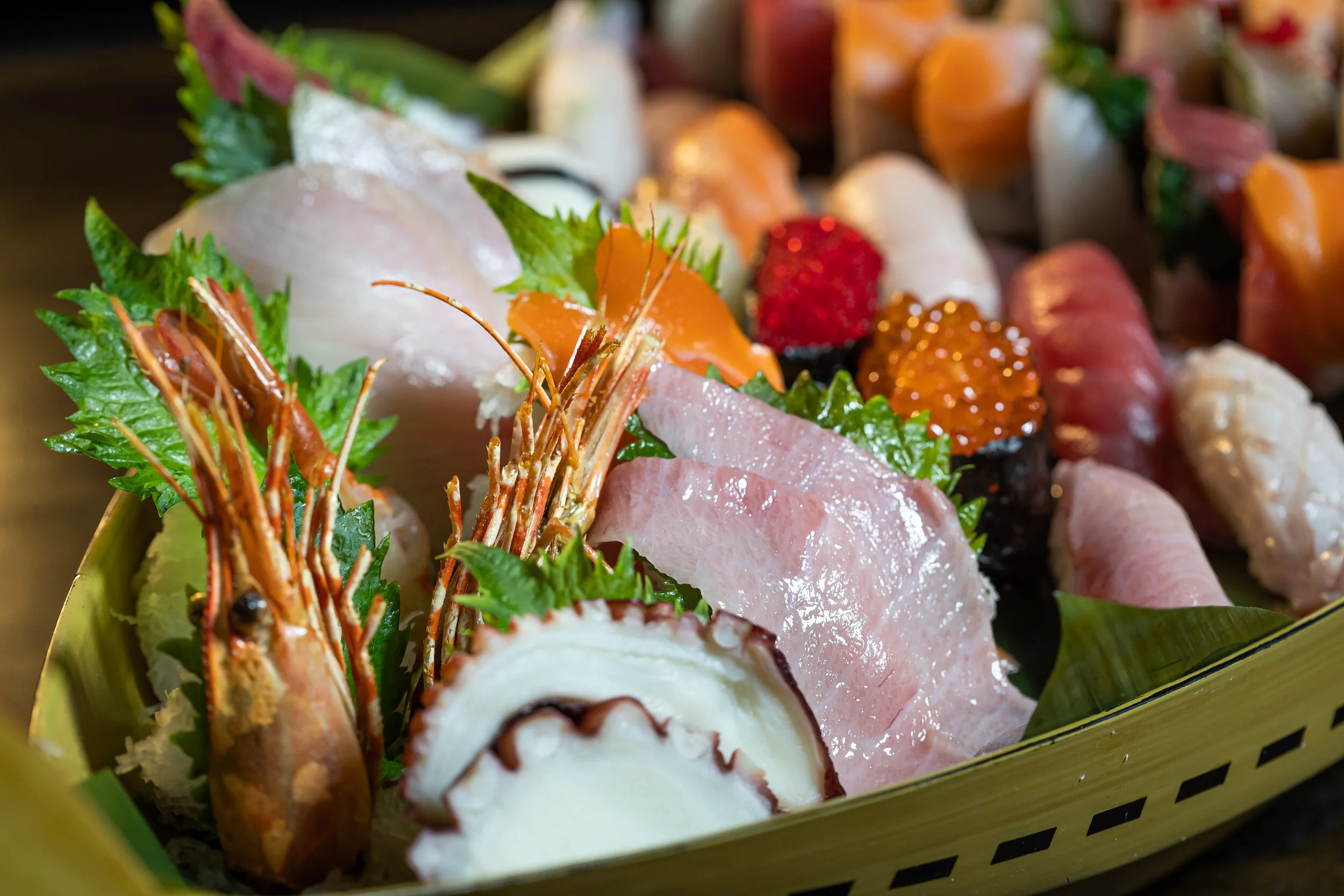 Sushi and sashimi boat close-up with shrimp, sliced fish and colorful rolls