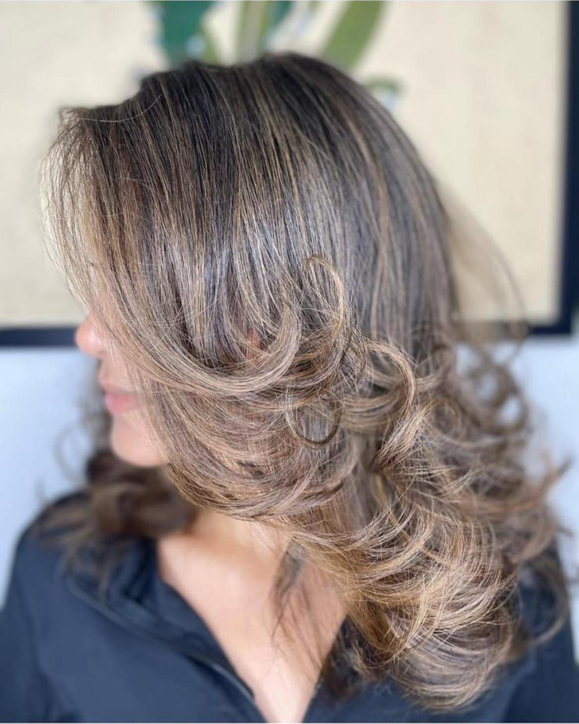Side profile of a layered brunette blowout with highlights