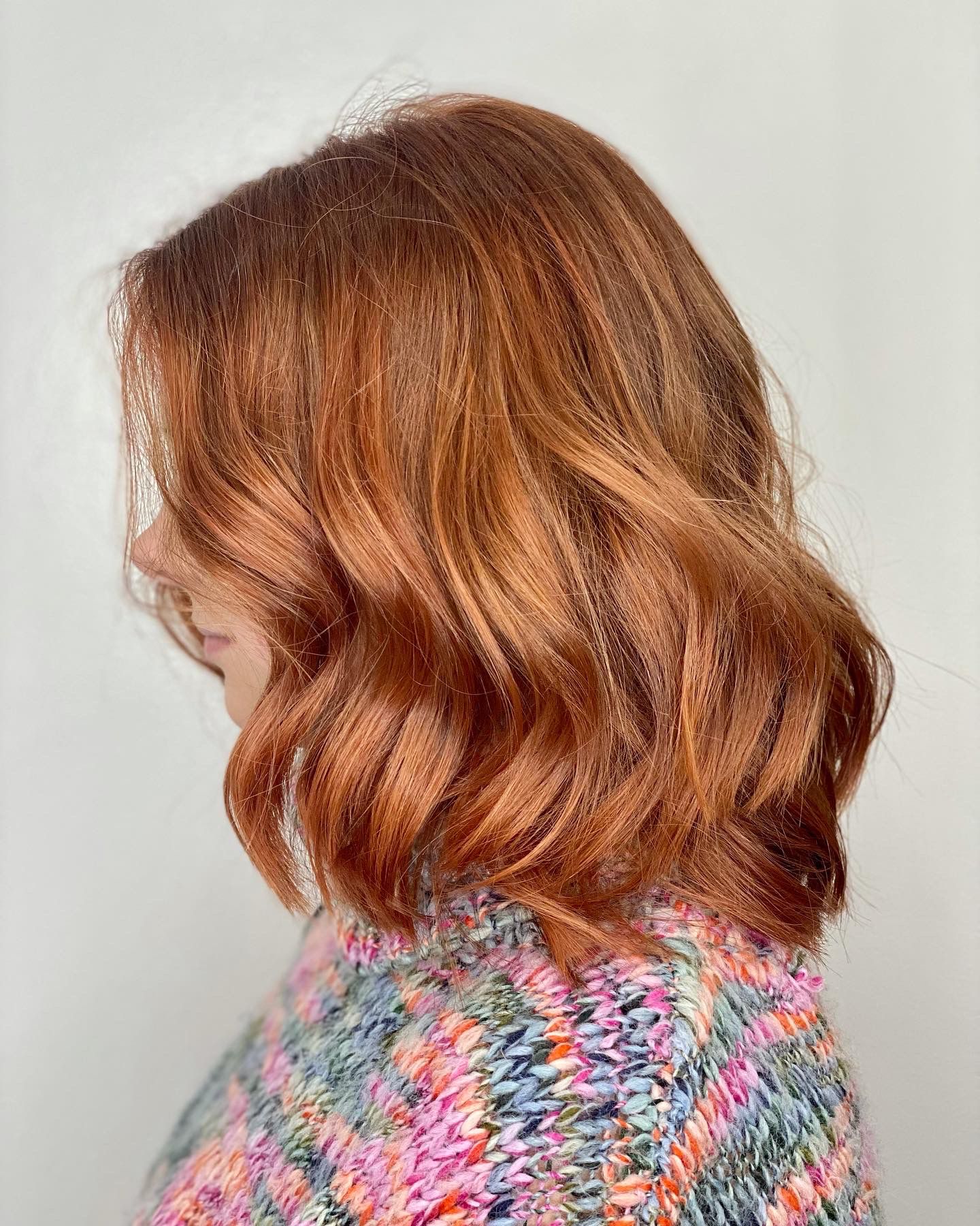 Side profile of a woman with a short wavy copper bob