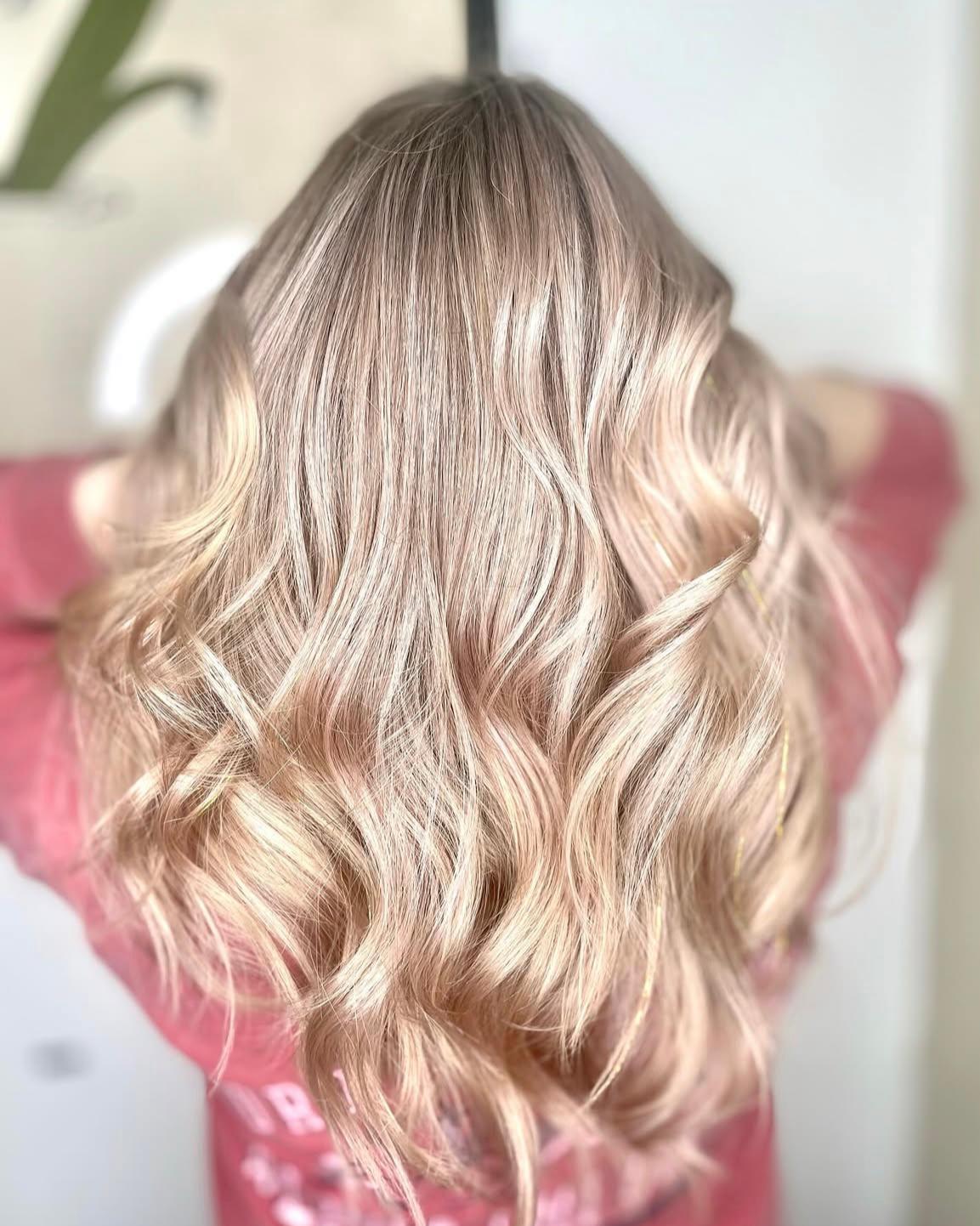Back view of long wavy rose gold blonde balayage