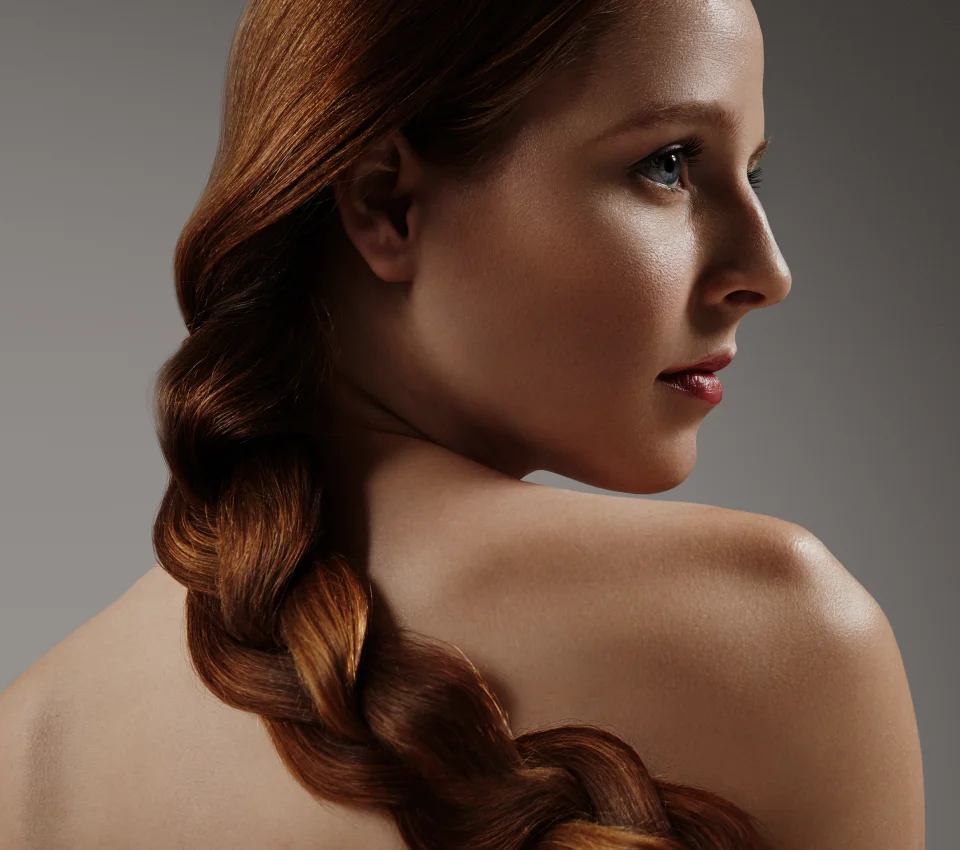 Profile portrait of a woman with auburn hair in a braided ponytail