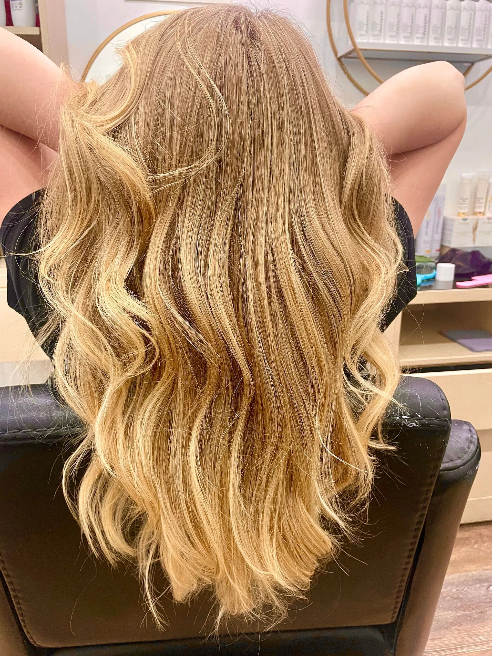 Back view of long wavy blonde hair in the salon chair