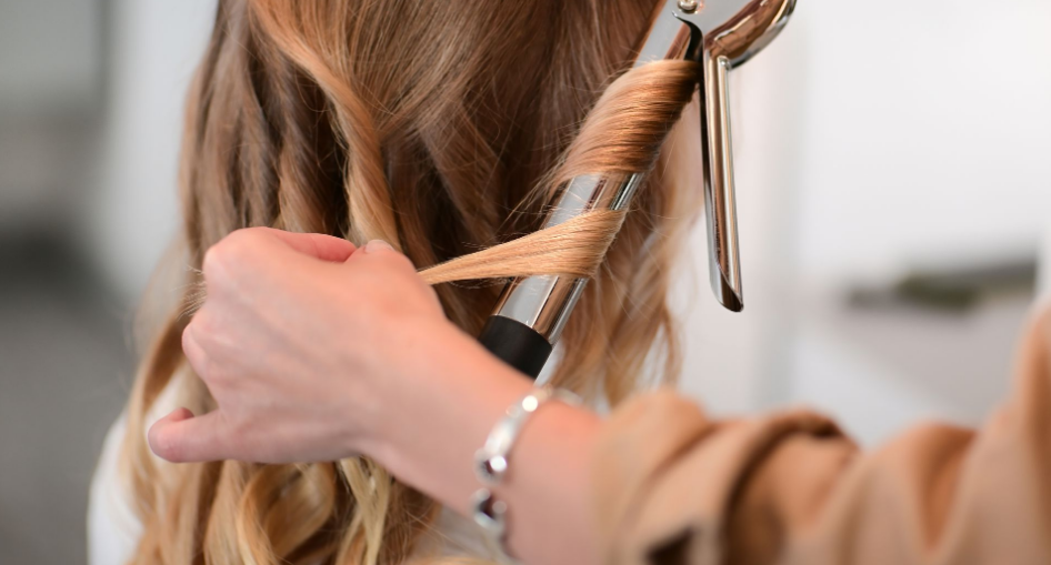 Stylist using a curling iron on a client's ombré blonde hair