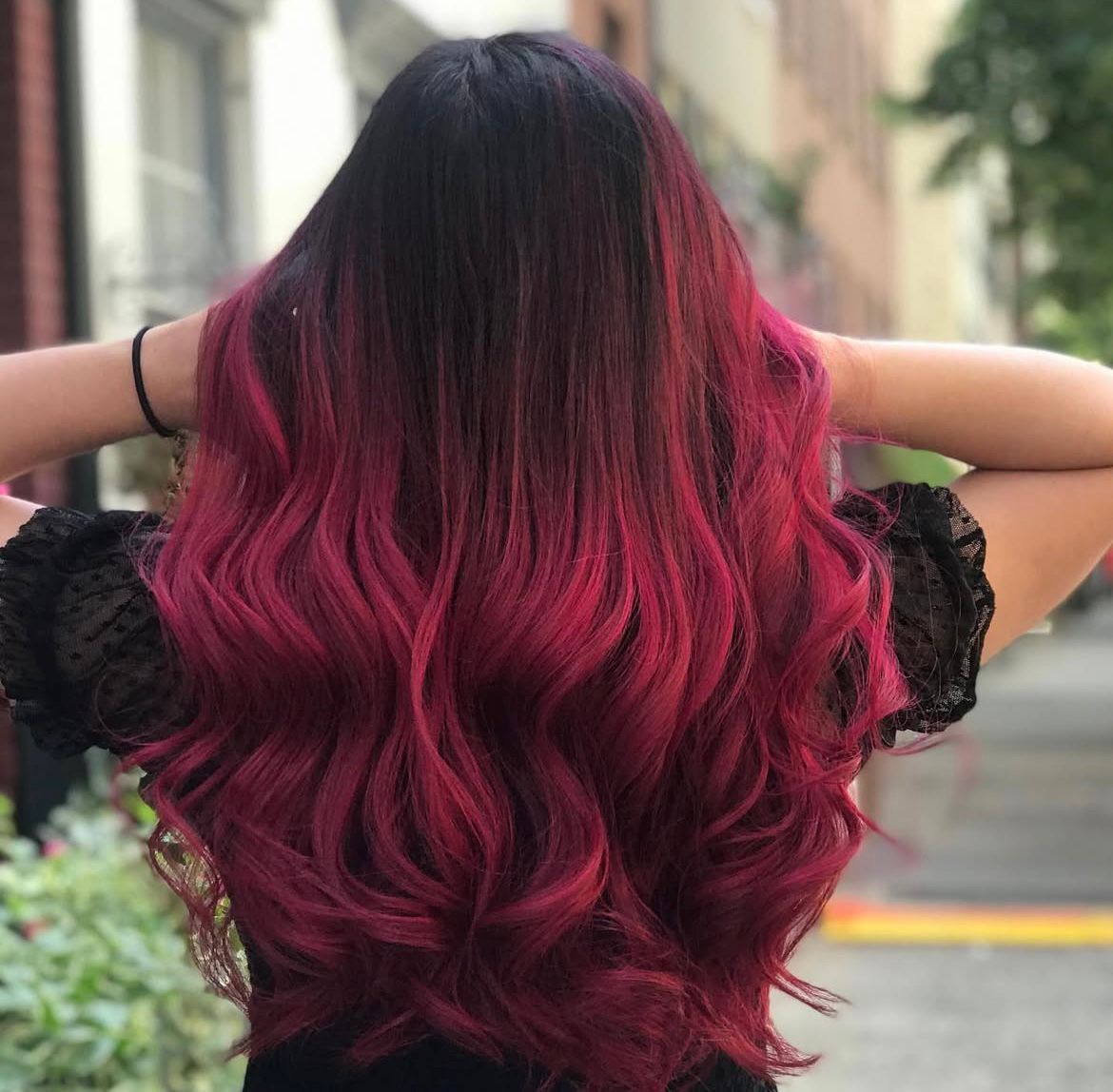 Back view of long wavy dark-to-cherry-red ombré hair