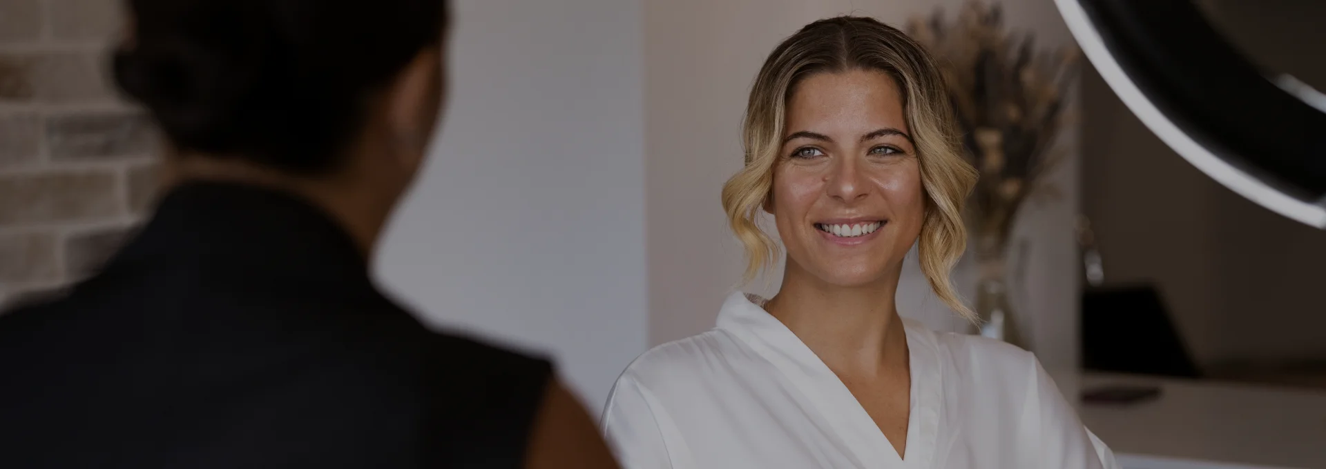 Smiling client looking at her reflection with her stylist behind her