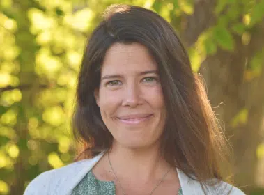 Kristin Meek, a WYLD Guide, smiling outdoors against a background of golden autumn foliage