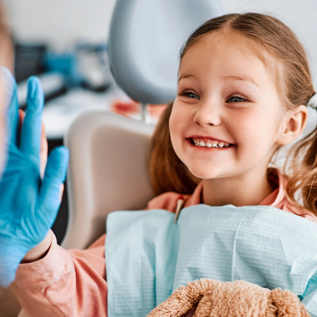 Child high-fiving a dentist in the chair — pediatric dentistry